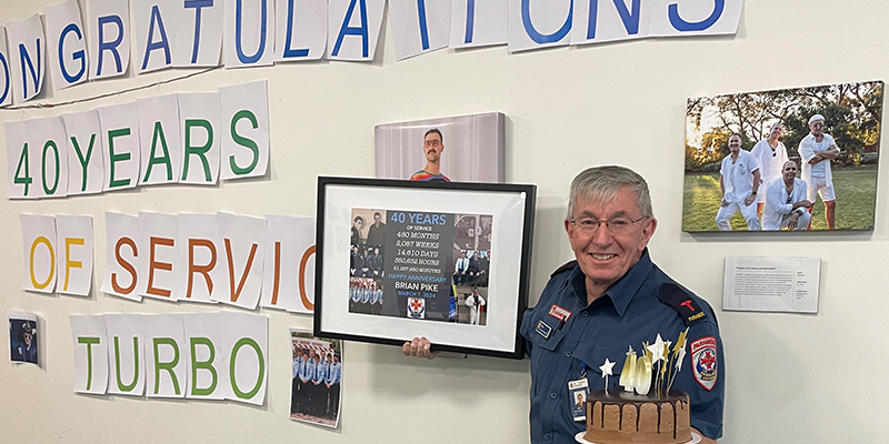 Brian Pike holding a cake and a picture frame commemorating his forty years of service with AV6K.