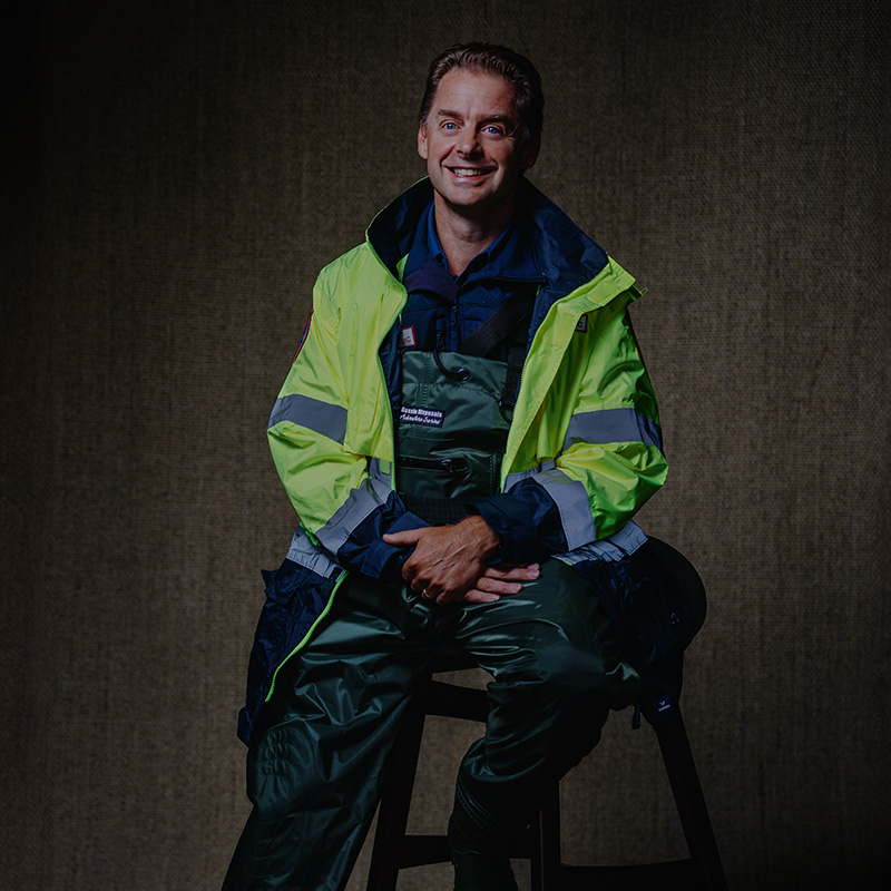 A portrait of AV6K Paramedic Educator Adrian Pensak with the waders he wore during the October 2022 floods.